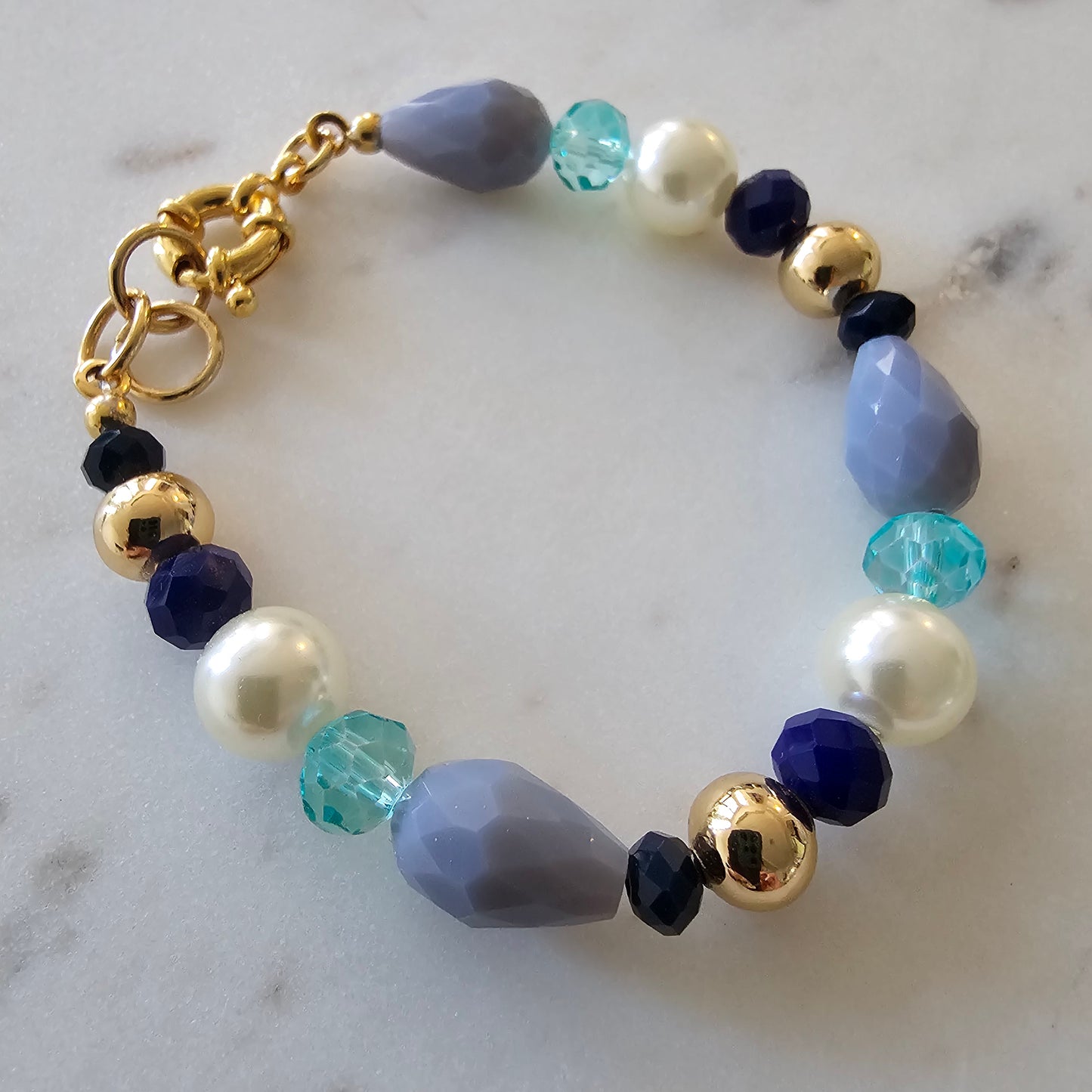 18K Gold Plated Bracelet with pearls, blue crystals, and gray stones.