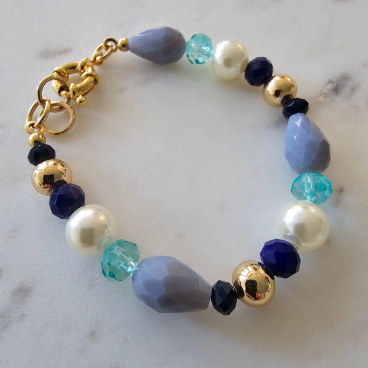 18K Gold Plated Bracelet with pearls, blue crystals, and gray stones.