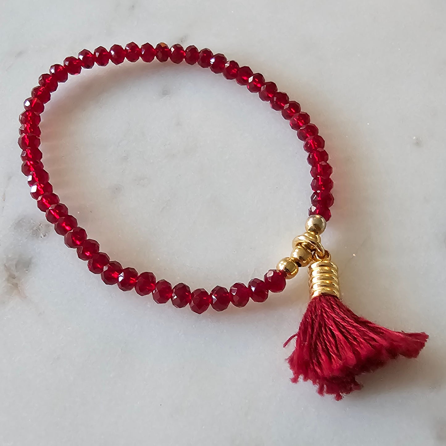 18K Gold Plated Bracelet with red crystals and pompom details.
