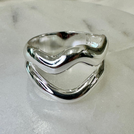 Silver ring with wavy design on a light gray background